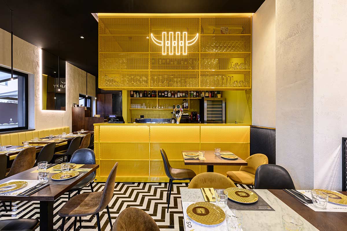 Sala interna con cubo giallo che racchiude i servizi e la zona bar
